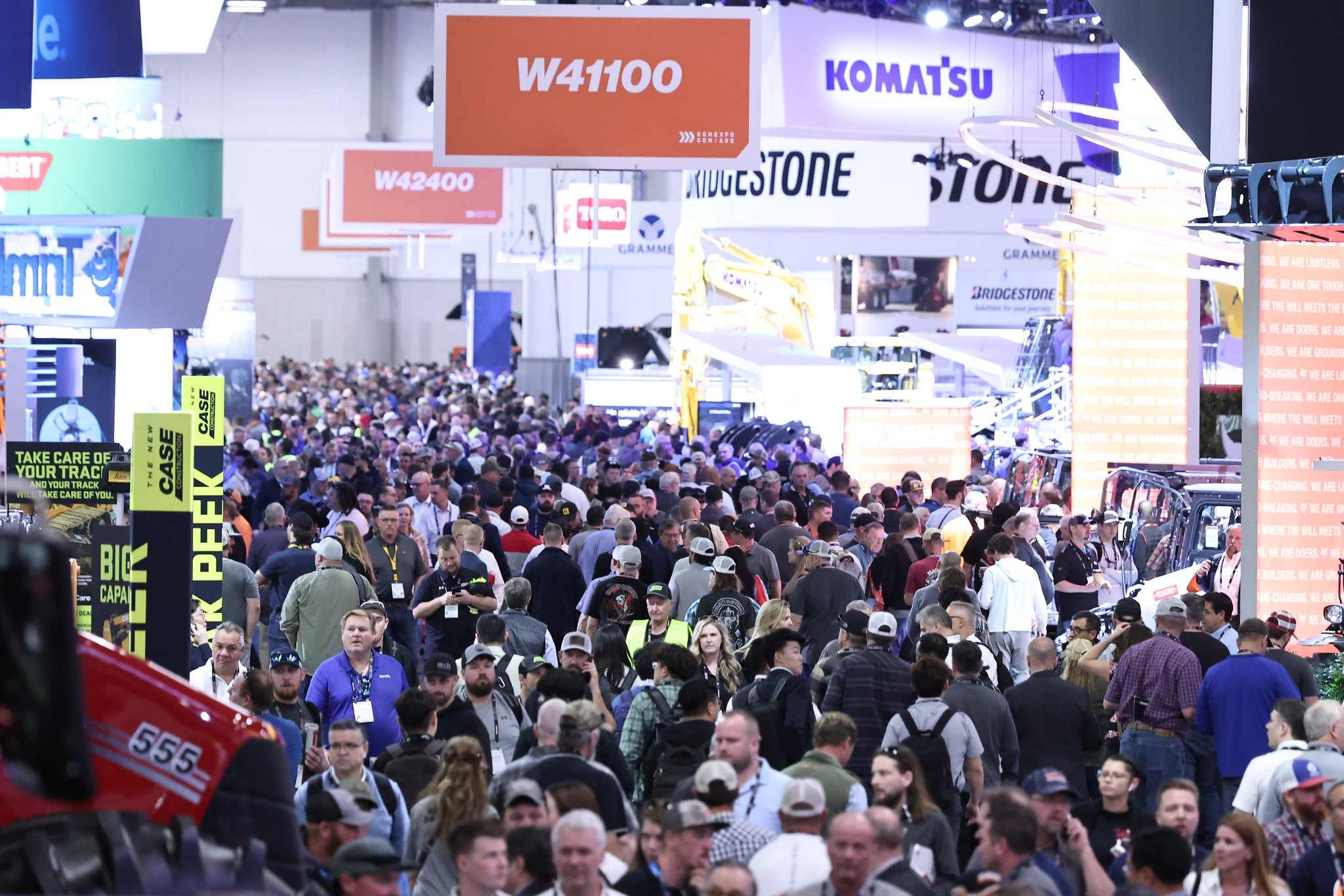 Crowded industrial trade show floor with Komatsu and Bridgestone displays
