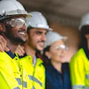 Construction workers in bright safety vests and hard hats standing together