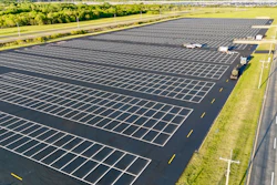 Aerial view of empty parking lot with white lines, next to highway and green landscape