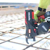 Construction worker using a red MAX nail gun on rebar at a job site
