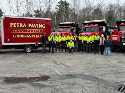 Petra Paving work crew in safety vests standing in front of red trucks and equipment