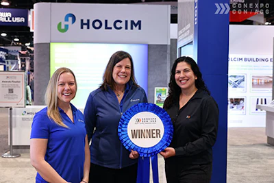 Holcim trade show booth with three professionals and winner ribbon