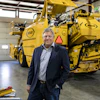 Executive standing in front of large yellow Weller industrial machinery in warehouse