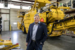 Executive standing in front of large yellow Weller industrial machinery in warehouse