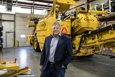 Executive standing in front of large yellow Weller industrial machinery in warehouse