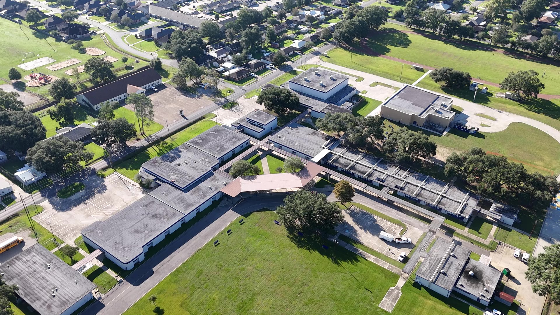 Aerial view of school campus with multiple buildings, trees, and green spaces