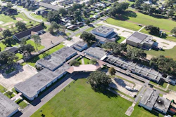 Aerial view of school campus with multiple buildings, trees, and green spaces