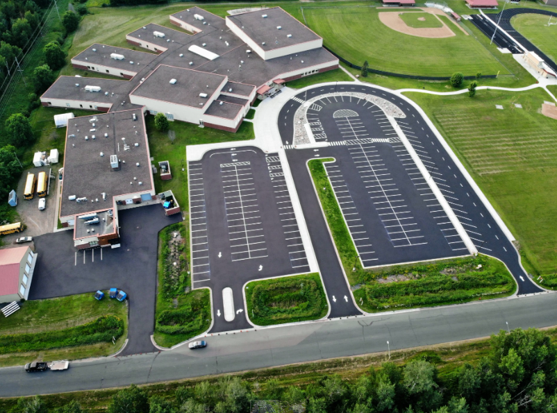 Aerial view of large parking lot complex with buildings and green landscaping