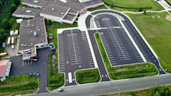 Aerial view of large parking lot complex with buildings and green landscaping