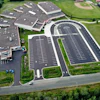 Aerial view of large parking lot complex with buildings and green landscaping