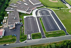 Aerial view of large parking lot complex with buildings and green landscaping