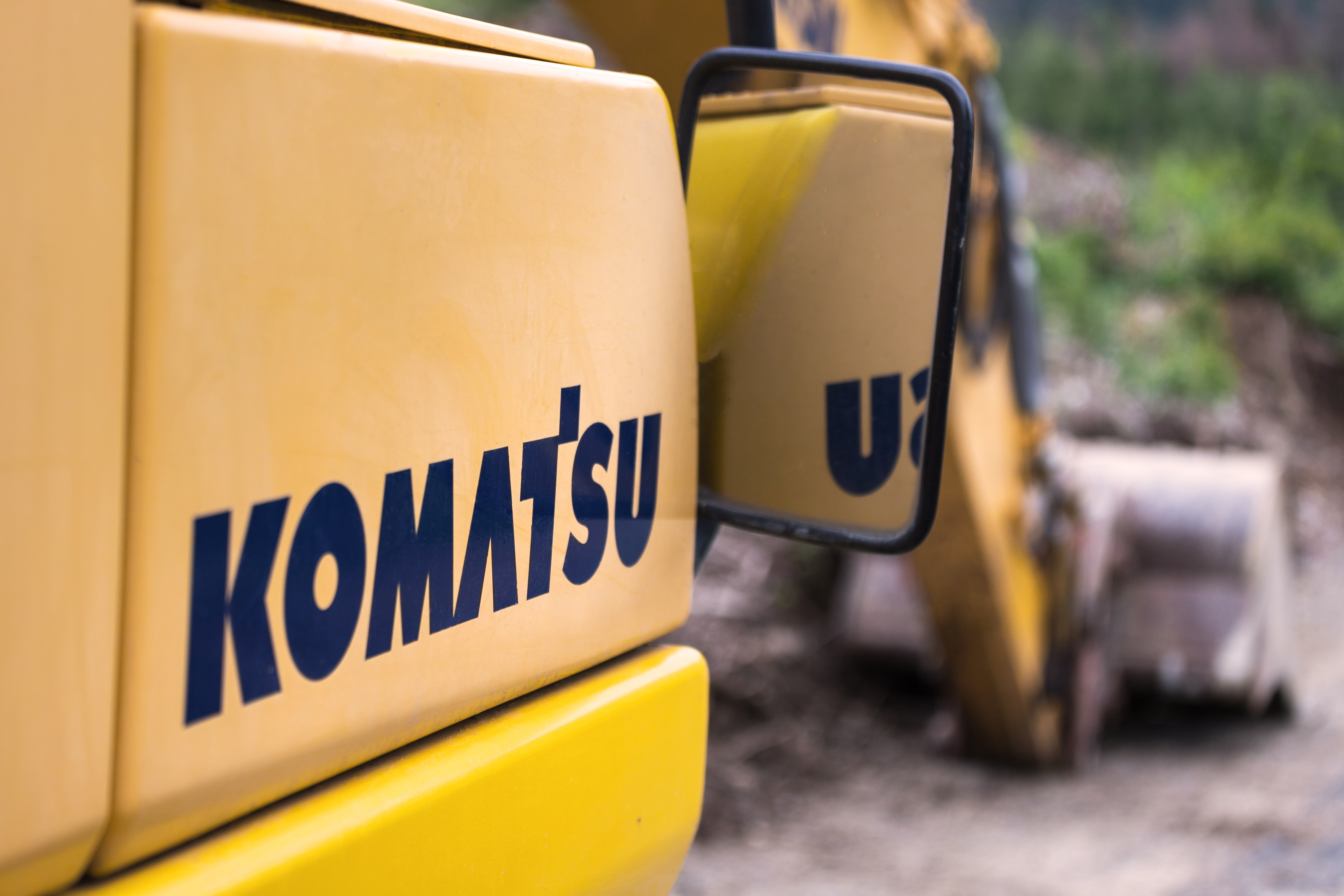 Yellow Komatsu construction machinery close-up with industrial background