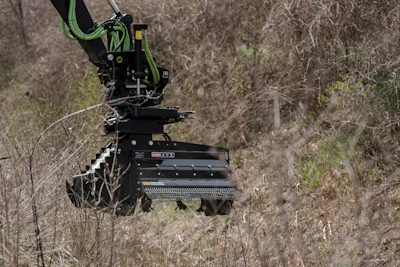 Robotic tracked vehicle with green mechanical arm in overgrown wilderness terrain