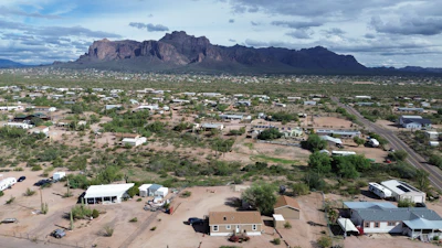 Desert town with suburban houses and rugged mountain range under cloudy sky