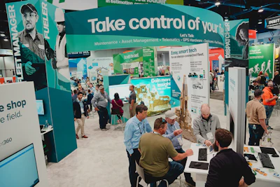 Trade show booth showcasing fleet management technology with attendees and displays