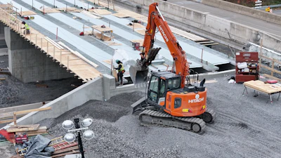 Orange Hitachi excavator working on bridge construction site with gravel and concrete