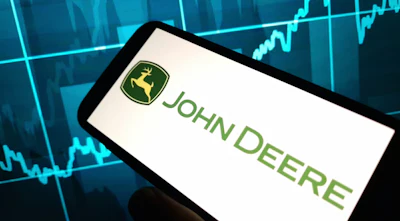 John Deere logo displayed on smartphone with financial market graph backdrop