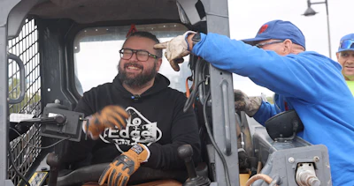 Construction worker smiling inside heavy machinery cabin wearing work gloves