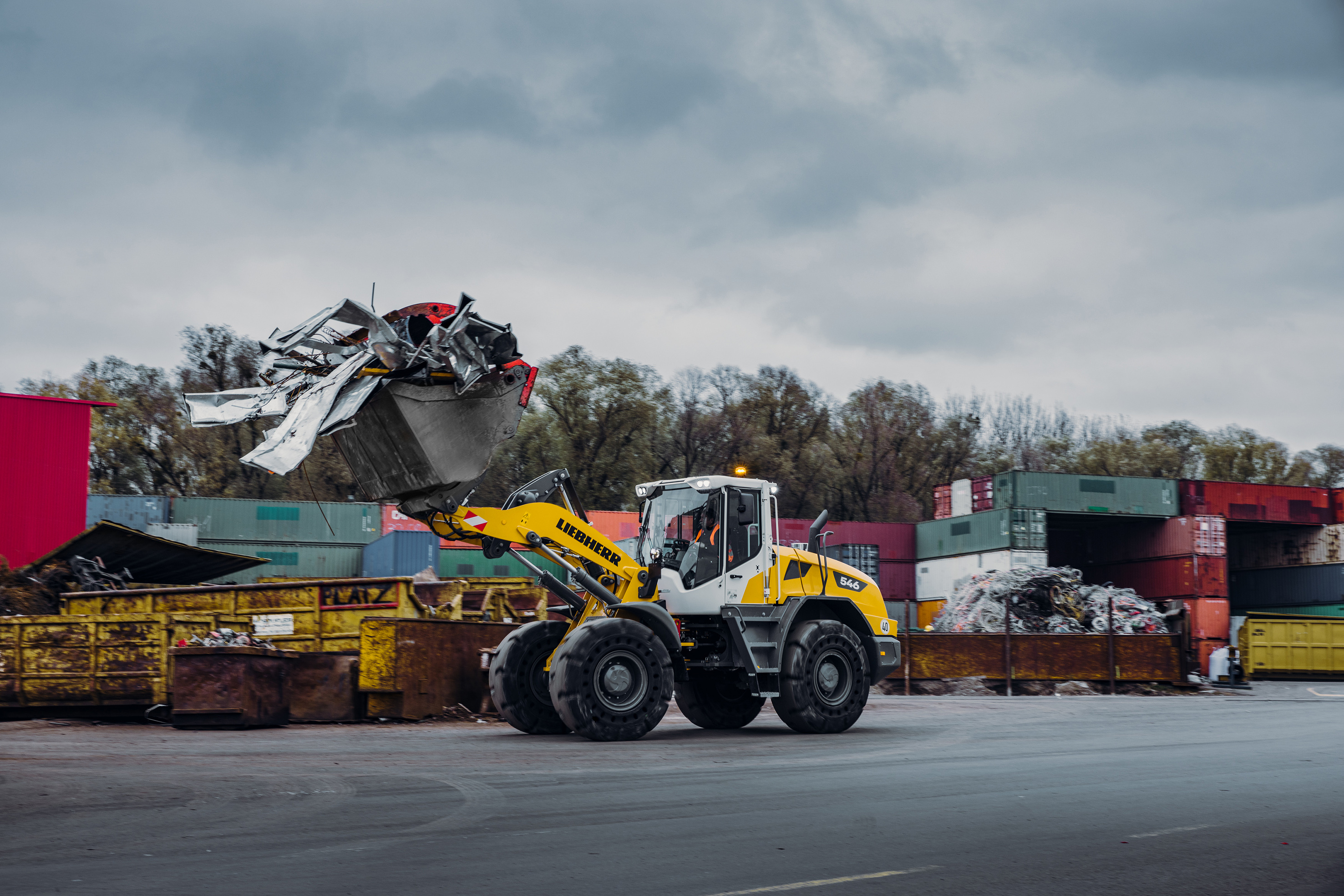 Yellow Liebherr wheel loader moving scrap metal at industrial recycling facility