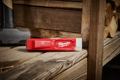 Red Milwaukee spirit level resting on wooden workbench in workshop