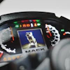 Mack Trucks logo on vehicle dashboard with illuminated instrument panel