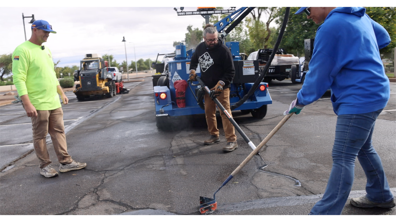 Construction workers repairing asphalt with blue equipment and machinery