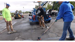 Construction workers repairing asphalt with blue equipment and machinery