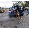 Construction workers repairing asphalt with blue equipment and machinery