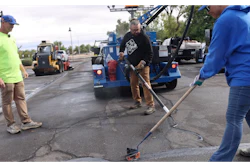 Construction workers repairing asphalt with blue equipment and machinery