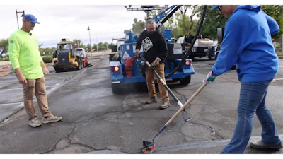 Construction workers repairing asphalt with blue equipment and machinery