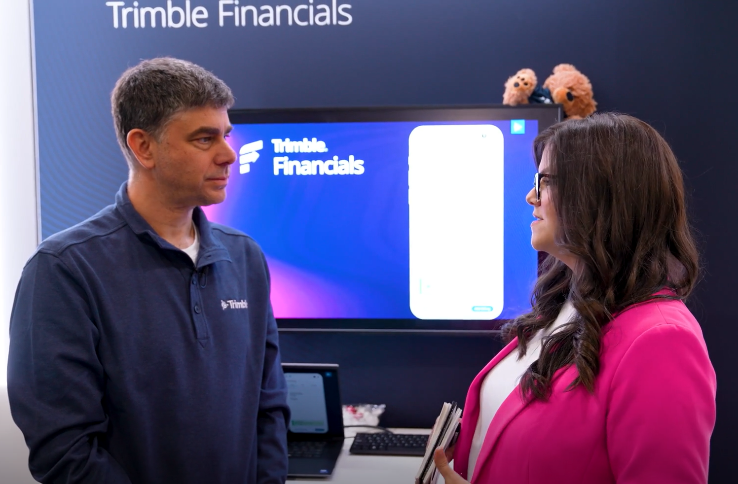 Two professionals discussing Trimble Financials presentation at corporate event