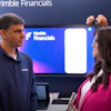 Two professionals discussing Trimble Financials presentation at corporate event