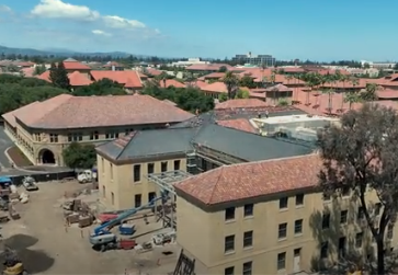 Aerial view of residential complex with terracotta-roofed buildings, parking areas, and surrounding urban landscape