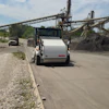 White Elgin concrete mixer truck at aggregate facility with conveyor belts and stockpiles