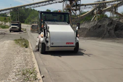 White Elgin concrete mixer truck at aggregate facility with conveyor belts and stockpiles