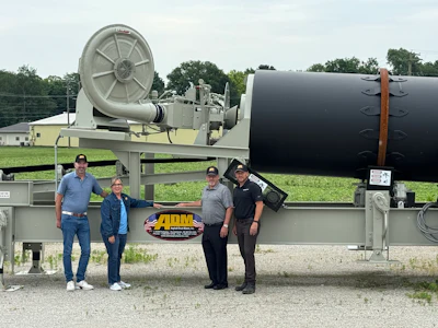 Four workers posing in front of large agricultural irrigation equipment with ADM branding