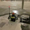 Construction worker in safety gear operating equipment in a parking garage with concrete pillars