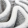 Close-up of coiled white rope with textured surface and curved organic forms