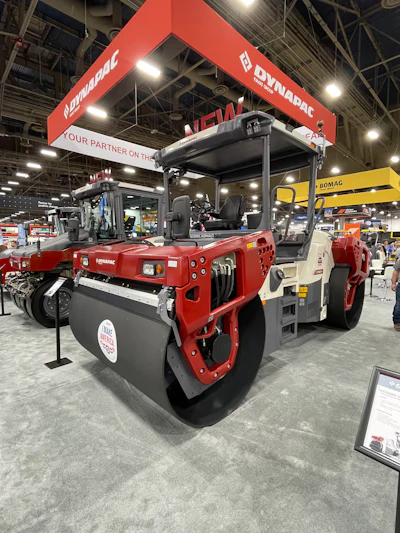 Red Dynapac asphalt roller compactor on display at industrial trade show with branded booth signage