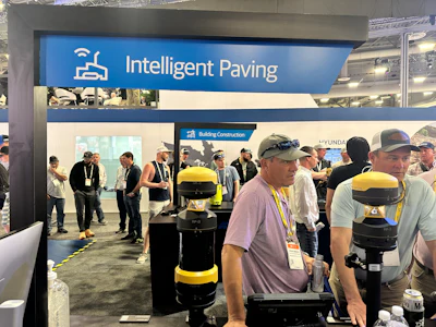 Intelligent Paving trade show booth featuring robotic paving equipment and visitors at construction industry exhibition