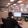 Professional working at dual-monitor workstation in modern office with headphones and technical displays