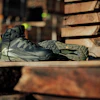 Gray and black HOKA hiking boot displayed on wooden logs in outdoor setting