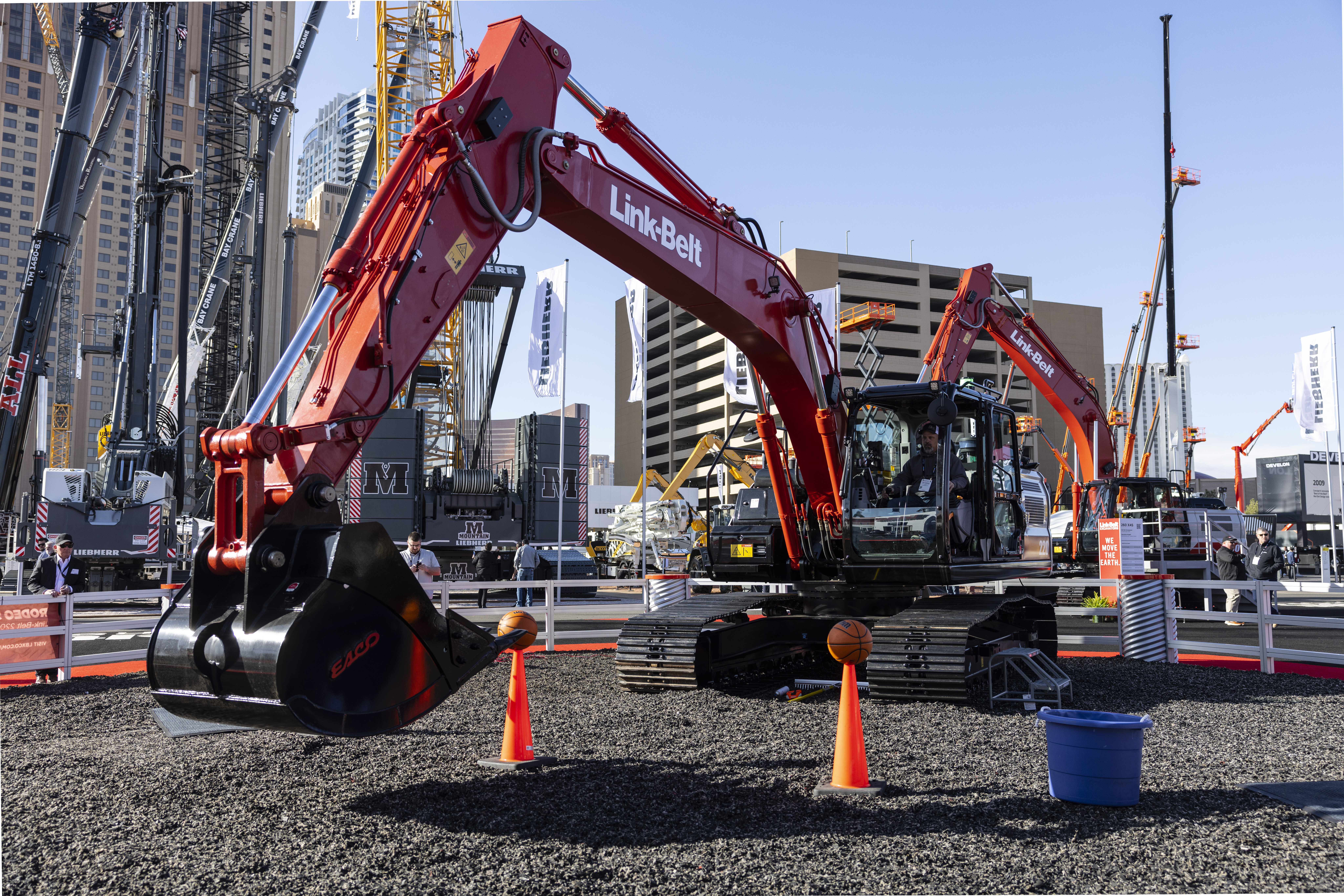 Red Link-Belt excavators displayed at outdoor construction equipment exhibition with city buildings in background