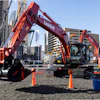 Red Link-Belt excavators displayed at outdoor construction equipment exhibition with city buildings in background