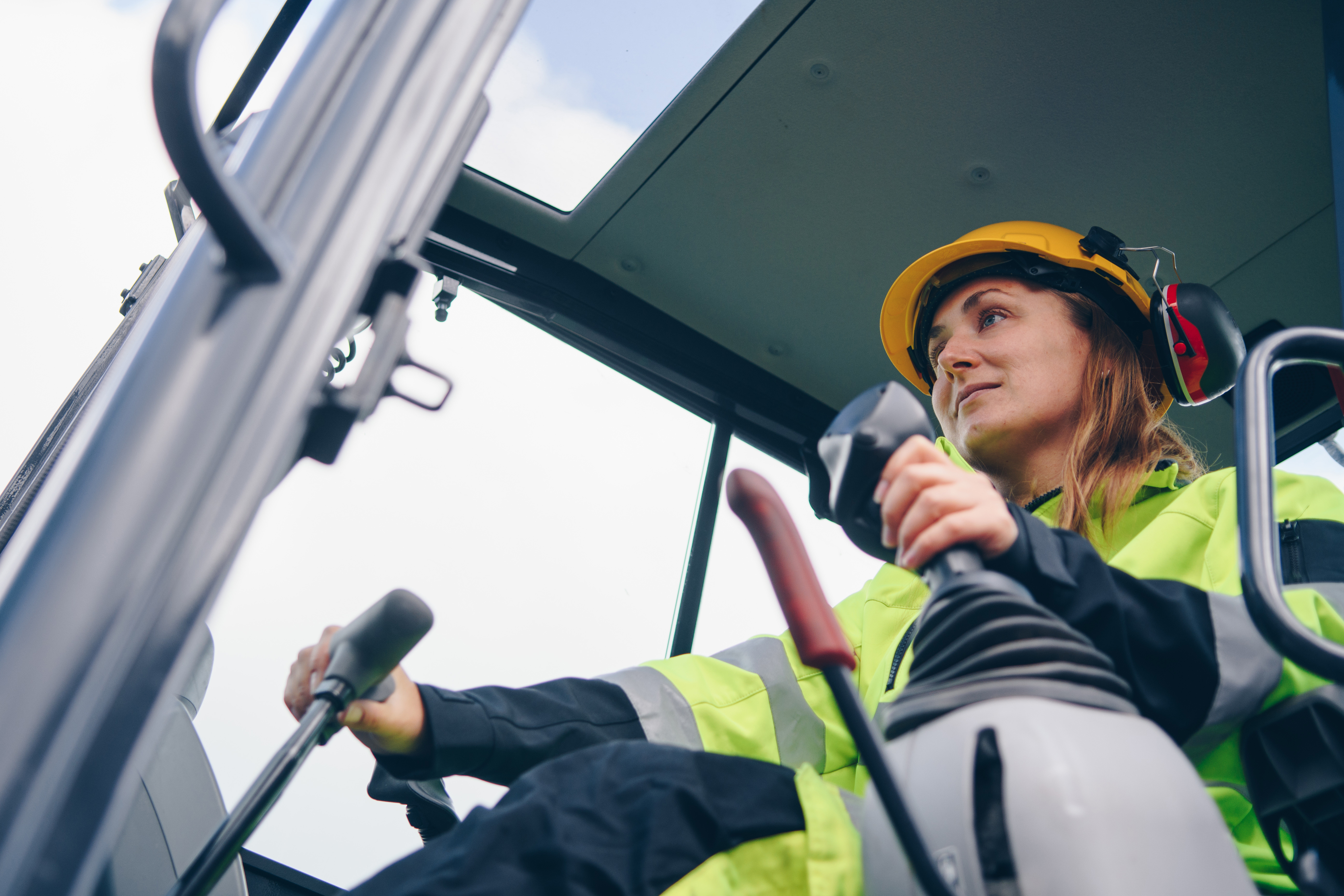 Female construction worker in safety gear operating heavy machinery on job site
