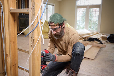 Electrician installing wiring in residential construction project with tools and materials