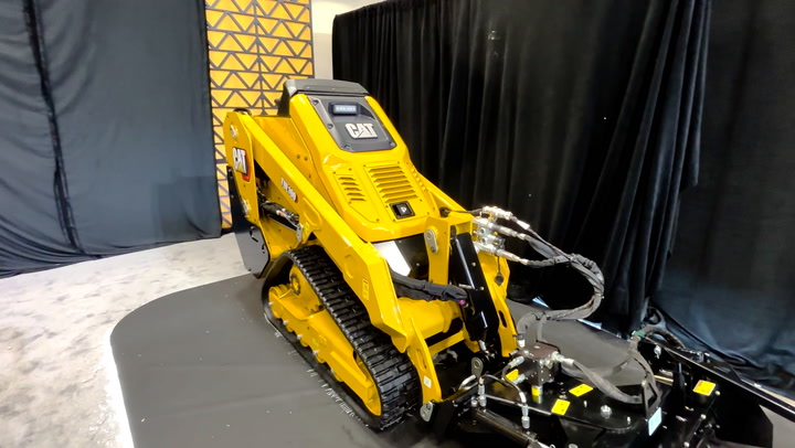 Yellow Caterpillar compact track loader on display in showroom with black curtain backdrop