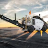 ROADTEC asphalt paving machine operating on a road at sunset with dramatic sky