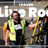 Worker in yellow safety vest holding measuring equipment on freshly paved asphalt road