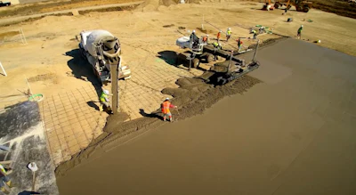 Construction workers pouring concrete at a job site with cement mixer truck and equipment